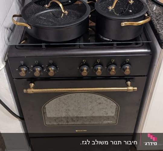תנור גז שחור עם סירים שחורים ומכסים שקופים